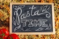 Chalk board sign Pasta Time on a wooden tabletop with raw farfalle, fresh tomatoes and black pepper Royalty Free Stock Photo