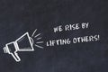 Chalk board sketch with loudspeaker and motivational phrase we rise by lifting others