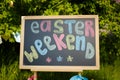 Chalk board standing outdoors with inscription Easter weekend. Royalty Free Stock Photo