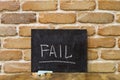 Chalk board with the word FAIL drown by hand and chalks on wooden table on brick wall background Royalty Free Stock Photo