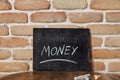 Chalk board with the word MONEY drown by hand on wooden table on brick wall background