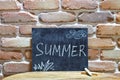 Chalk board with the word SUMMER drown by hand and chalks on wooden table on brick wall background Royalty Free Stock Photo