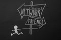 Chalk drawing of human figure near sign with words SOCIAL NETWORK and FRIENDS on black background, top view. Loneliness concept