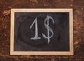 Chalk handwritten dollar sign on blackboard on wooden background