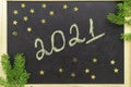 Chalk handwritten inscription 2021 on a black board. With golden stars.