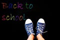 chalk and kid& x27;s feet on black background wearing sneakers - back to school concept