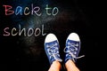 chalk and kid& x27;s feet on black background wearing sneakers - back to school concept