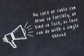 Chalk loudspeaker and wise quote on black desk