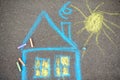 Chalk picture of house and sun on asphalt of sidewalk. Kids creative picture on gray background of road Royalty Free Stock Photo