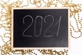 A chalk plaque with the inscription 2021, around the golden beads. New Year's Eve Royalty Free Stock Photo