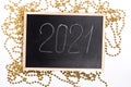 A chalk plaque with the inscription 2021, around the golden beads. New Year's Eve Royalty Free Stock Photo