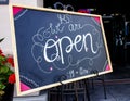 Chalk sign at resturant in welcoming artisitic cursive writing stating Yes We Are Open