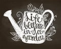 Chalk silhouette of vintage watering can with leaves and flowers and lettering - Life began in a garden on chalk board.