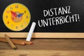 Chalkboard with clock and wooden pencils and the german words for distance learning, distance education or home schooling - distan Royalty Free Stock Photo