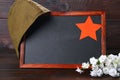 Chalkboard with empty space, military cap and red star on a wood