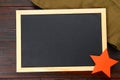 Chalkboard with empty space, military cap and red star on a wooden table. Day of the defender of the fatherland and May 9.
