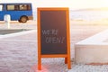 Chalkboard menu black color with an inscription - we are open. Mockup is standing near the restaurant on sea beach. Sunny day Royalty Free Stock Photo