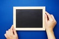 Chalkboard mock up. Female hands holding blackboard on a blue background, isolated. Copy space, flat lay. Business, education