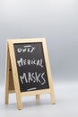 Chalkboard from an oblique perspective with the words only medical masks necessary for shopping in the shop