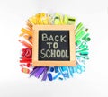 Chalkboard with phrase `BACK TO SCHOOL` and different stationery on white background, top