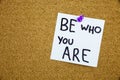 A yellow sticky note writing, caption, inscription chalkboard with the phrase be who are you in black ext on a sticky