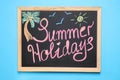 Chalkboard with phrase SUMMER HOLIDAYS on background, top view. School`s out