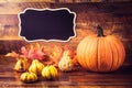 Chalkboard, pumpkins and leaves over old wooden background with copy space Royalty Free Stock Photo