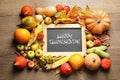 Chalkboard with text THANKSGIVING DAY, autumn vegetables and fruits on wooden table. Happy holiday Royalty Free Stock Photo