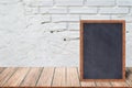 Chalkboard wood frame, blackboard sign menu on wooden table and with brick background. Royalty Free Stock Photo