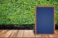 Chalkboard wood frame, blackboard sign menu on wooden table and grass wall background. Royalty Free Stock Photo