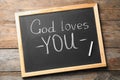 Chalkboard with words GOD LOVES YOU on wooden background Royalty Free Stock Photo