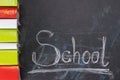 On the chalkboard written the word school and on the left vertically lie in a row of books Royalty Free Stock Photo