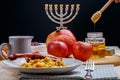 challah, wine, apples and honey dripping honey from a spoon into a jar.