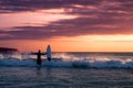 Challenge and conquer the concept: a silhouette of a surfer holding a Board and looking at the ocean Royalty Free Stock Photo