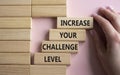 Challenge Level symbol. Concept word Increase your Challenge Level on wooden blocks. Beautiful pink background. Businessman hand.