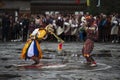 A Cham dancer with deer mask bending his body , a joker behind him and copy his motion , Haa Tshechu , Bhutan