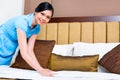 Chambermaid making bed in Asian hotel room Royalty Free Stock Photo