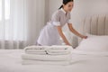 Chambermaid making bed in hotel, focus on fresh towels. Space for text Royalty Free Stock Photo