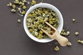 Chamomile dried herb flower tea in a white bowl on dark background with blossoms and buds nearby Royalty Free Stock Photo
