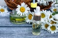 Chamomile essential oil in a glass jar and a bottle near chamomile