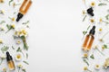 Chamomile flowers and cosmetic bottles of essential oil on white background, top view