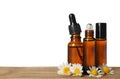 Chamomile flowers and cosmetic bottles of essential oil on wooden table against white background Royalty Free Stock Photo