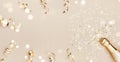 Champagne bottle with confetti stars, bokeh decoration and party streamers on golden background. Christmas flat lay