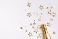 Champagne bottle with confetti stars and party streamers on festive background. Christmas, birthday or wedding concept. Flat lay Royalty Free Stock Photo