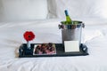Champagne and chocolate strawberries on bed
