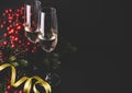 Champagne flutes and christmas decoration with conifer tree, red berries and pinecone on black background. Luxury holiday Royalty Free Stock Photo