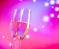 Champagne flutes with gold bubbles on blue and violet tint light background Royalty Free Stock Photo