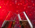 Champagne flutes with gold bubbles on red light bokeh background Royalty Free Stock Photo