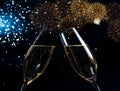 Champagne flutes with golden bubbles on blue light bokeh and fireworks sparkle background