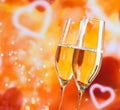 Champagne flutes with golden bubbles on blur decorative hearts background Royalty Free Stock Photo